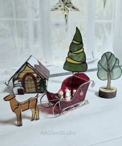 Sleigh with reindeer in a snowy village street, surrounded by snow-covered trees and festive evergreens.