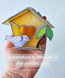 Miniature stained glass birdhouse wedding gift held in hand with purple bird, yellow walls and heart design by AAGlassStudio