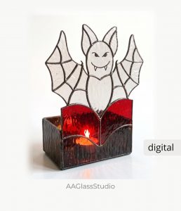 Spooky spider web stained glass candle holder with a green cabochon spider on a white background