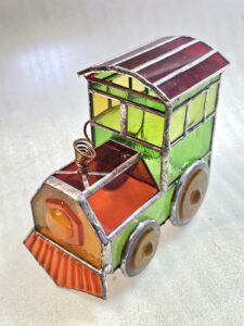 Front three quarter view of the completed 3D stained glass toy train locomotive with a spiral copper wire smokestack
