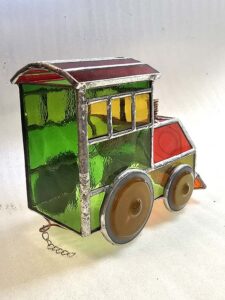 Back and side view of the finished 3D stained glass locomotive showing the curved red roof and the copper coupling loop at the base