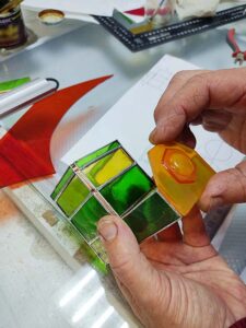 Attaching the round amber stained glass headlight to the front of the foil wrapped stained glass locomotive panel