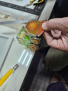 Holding the orange stained glass cowcatcher against the front of the locomotive and checking that it clears the wheels