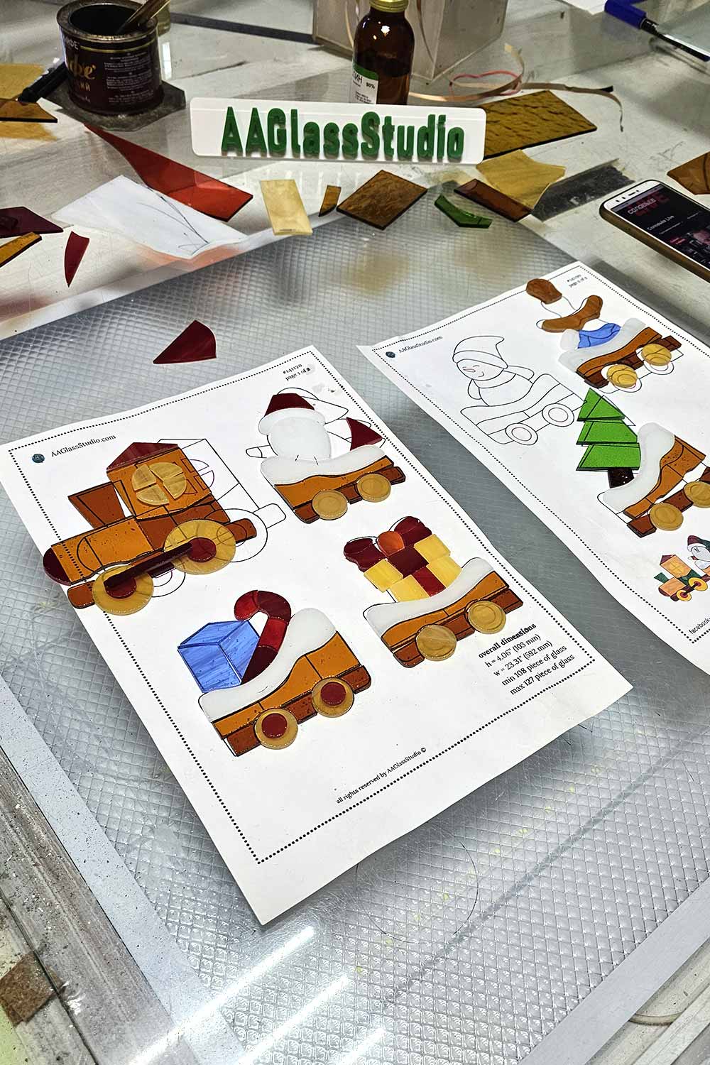 Cut and foiled stained glass pieces laid out on the printed Christmas train pattern before assembly