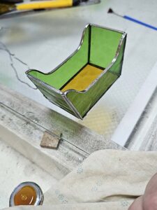 The first stained glass train wagon body assembled with green sides and an amber floor, copper foil seams still visible